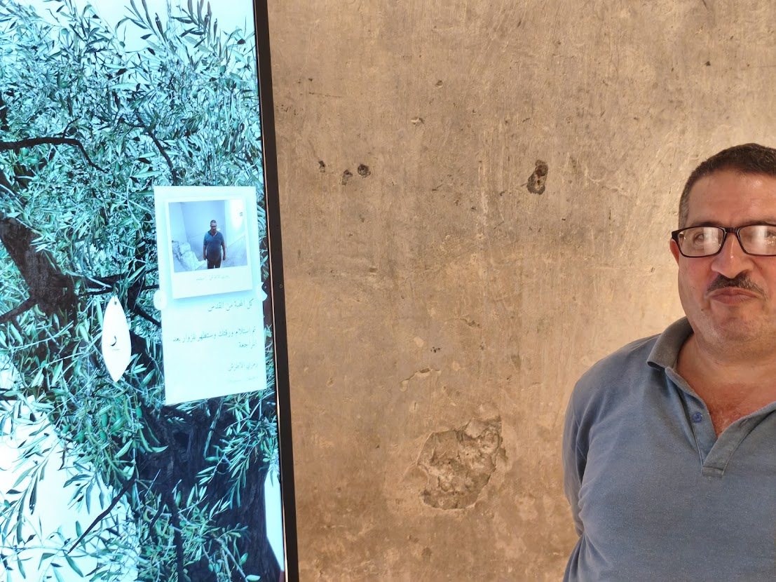 A visitor beside his own Arabic message and photo on a Guestbook leaf
